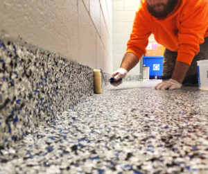 A Floor Skinz installer applies product to the base of a wall